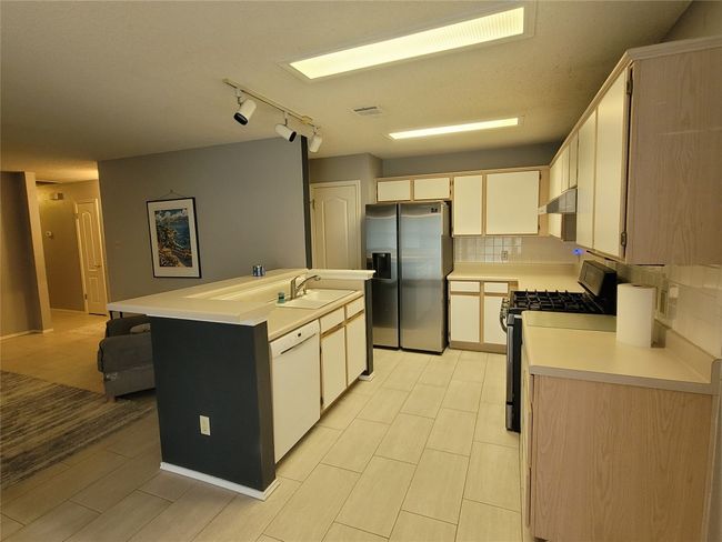 Kitchen featuring appliances with stainless steel finishes, backsplash, light countertops, and an under cabinet range hood | Image 7