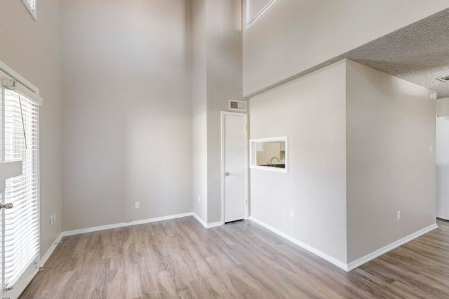 Spare room with a high ceiling, wood finished floors, visible vents, and baseboards | Image 17