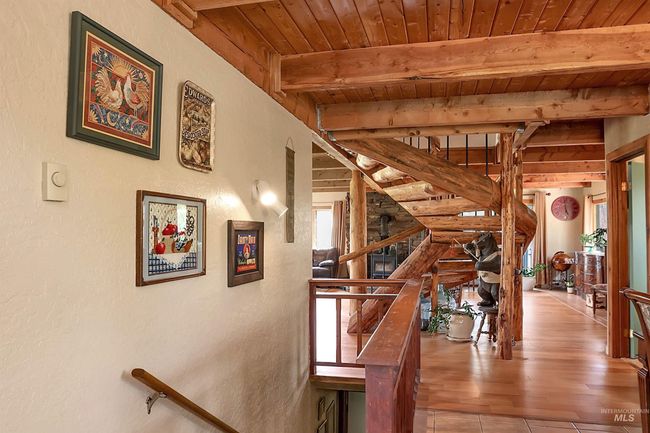 Staircase featuring a wood ceiling with exposed beams, a textured wall, and wood finished floors | Image 17
