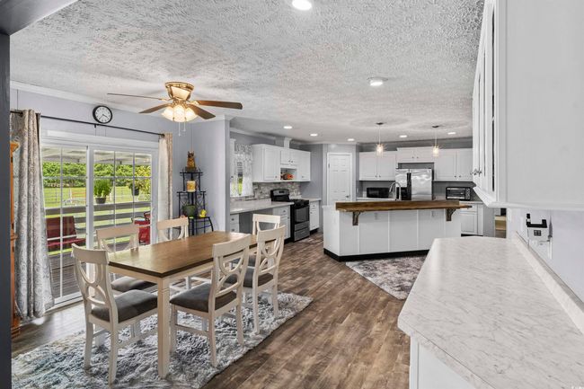 Dining room with a ceiling fan, a textured ceiling, recessed lighting, dark wood-style flooring, and crown molding | Image 35