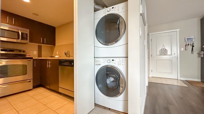 Washroom with stacked washer and clothes dryer, laundry area, and light tile patterned floors | Image 6