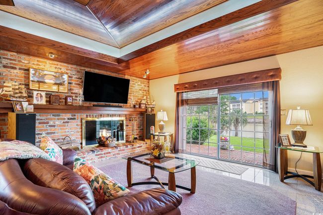 Living room featuring wooden ceiling, a brick fireplace, and baseboards | Image 15