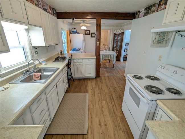 Kitchen with white cabinets, a sink, light wood-style floors, white appliances, and light countertops | Image 18