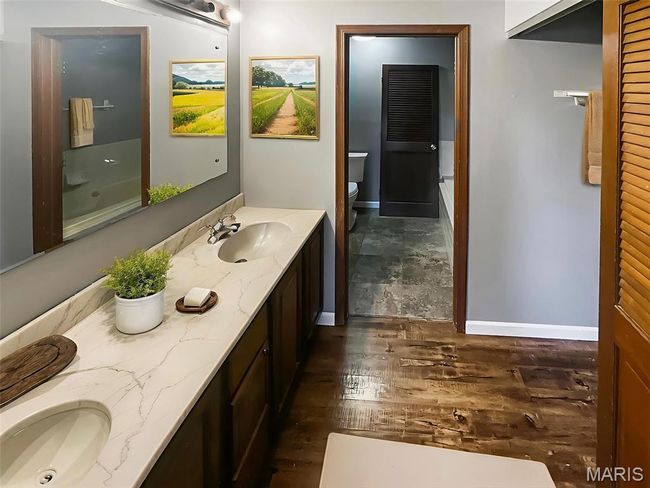 Full bath with double vanity, a bathtub, and wood finished floors | Image 8