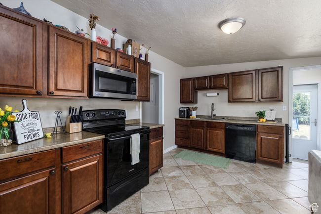 Kitchen featuring black appliances and a textured ceiling | Image 6