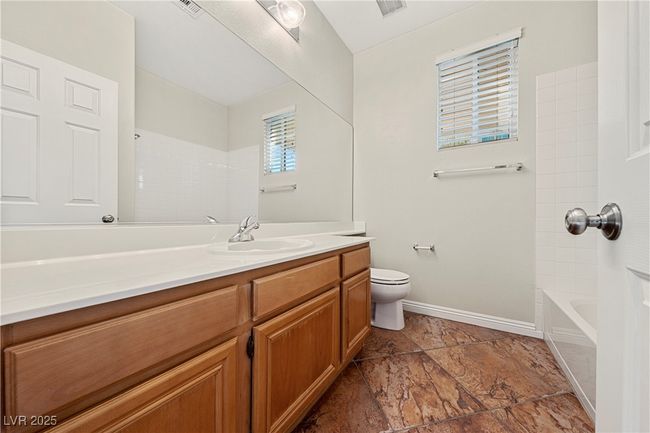 Full bathroom featuring vanity, stone tile floors, and shower / bath combination | Image 22