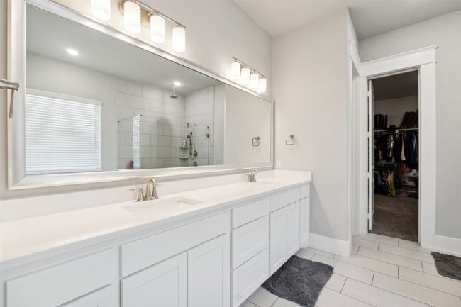Bathroom featuring a tile shower, double vanity, tile patterned floors, and a walk in closet | Image 20