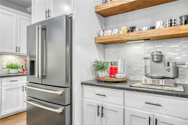 Kitchen featuring high end fridge, tasteful backsplash, dark stone countertops, light wood-type flooring, and white cabinets | Image 19