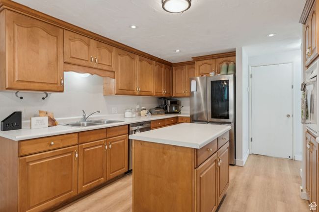Kitchen featuring appliances with stainless steel finishes, a sink, light countertops, and light wood-type flooring | Image 8