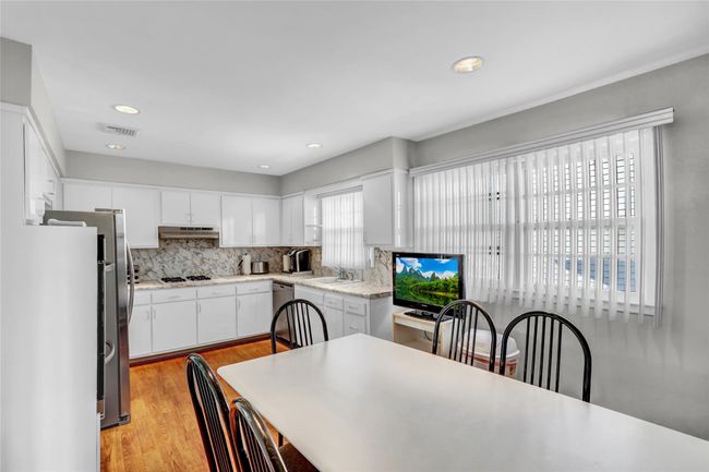 Kitchen featuring backsplash, dishwasher, light hardwood / wood-style flooring, and white cabinets | Image 11