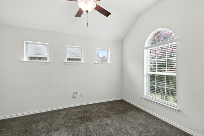 Empty room featuring lofted ceiling, a ceiling fan, and dark carpet | Image 8