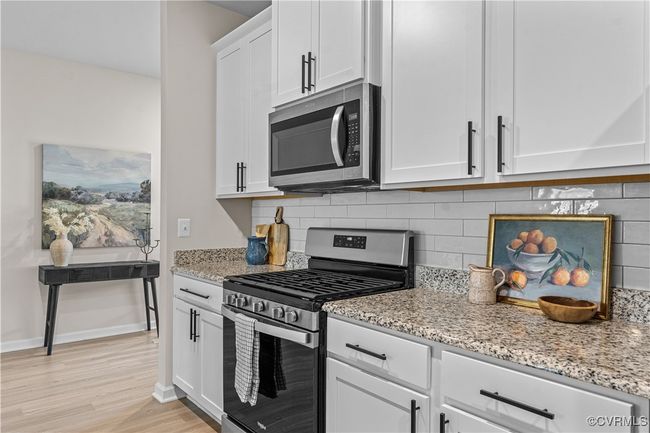 Kitchen featuring stainless steel appliances, decorative backsplash, light wood-style floors, and light stone counters | Image 14