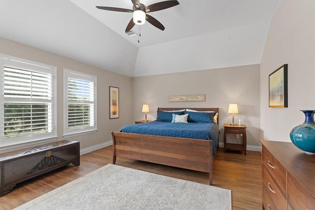 Upstairs Primary Bedroom featuring vaulted ceiling, light wood-type flooring, baseboards, and a ceiling fan | Image 15