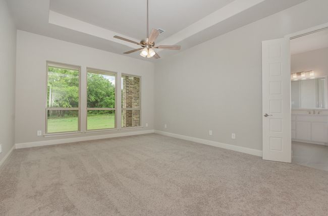 Unfurnished bedroom featuring carpet, baseboards, a sink, and a tray ceiling | Image 11