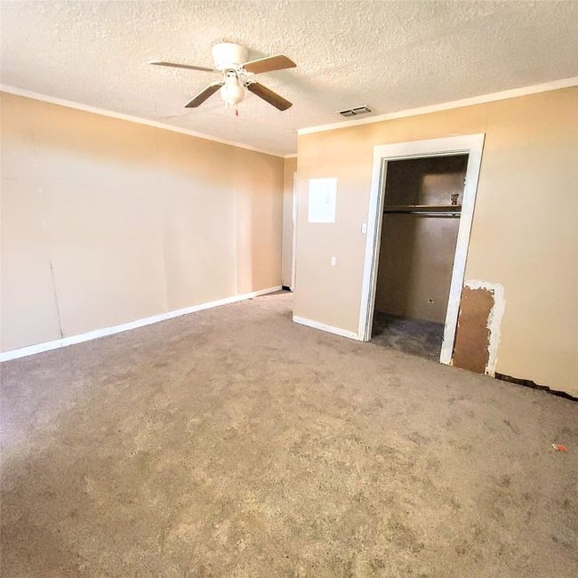 Unfurnished bedroom featuring crown molding, a textured ceiling, carpet floors, a ceiling fan, and a closet | Image 6