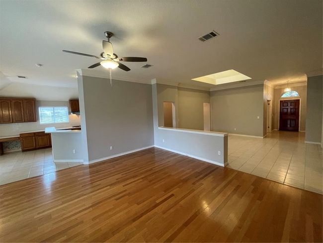 Unfurnished living room with light wood-style floors, a skylight, ceiling fan, and crown molding | Image 19
