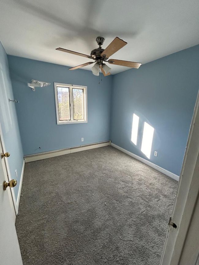 Carpeted spare room with ceiling fan and a baseboard radiator | Image 11