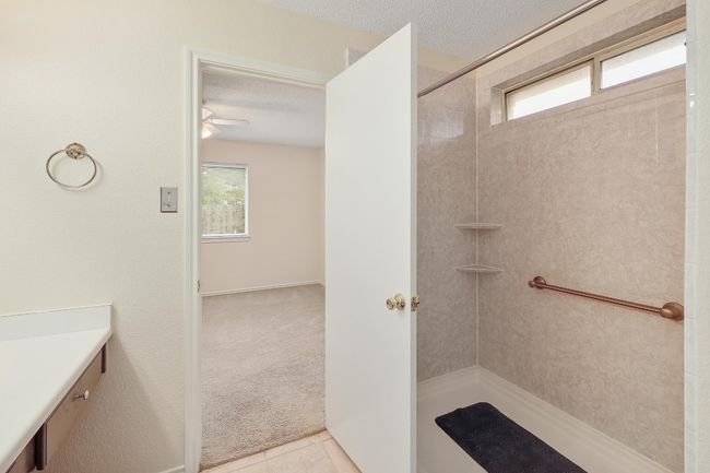 Bathroom featuring tiled shower, vanity, a textured ceiling, a ceiling fan, and tile patterned flooring | Image 17