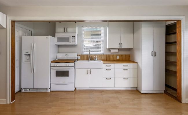 Kitchen with white appliances, a sink, light wood-style flooring, and light countertops | Image 25