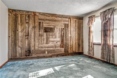 Living room with barn wood wall, carpet floors, and a textured ceiling | Image 3