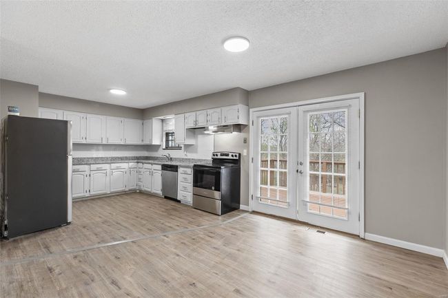 Kitchen featuring white cabinetry, light wood-type flooring, french doors, baseboards, and appliances with stainless steel finishes | Image 8
