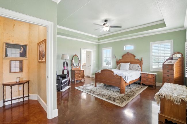 Bedroom featuring finished concrete flooring, crown molding, and ceiling fan | Image 15