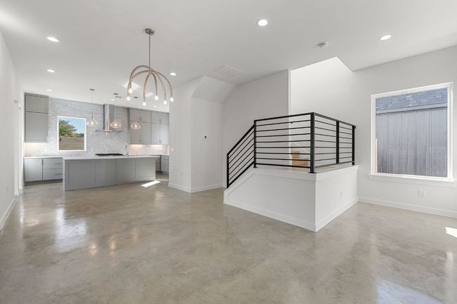 Unfurnished living room featuring finished concrete flooring, stairway, baseboards, and recessed lighting | Image 4