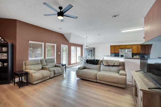 Living room featuring light wood-style flooring, a textured ceiling, lofted ceiling, and a ceiling fan | Image 7
