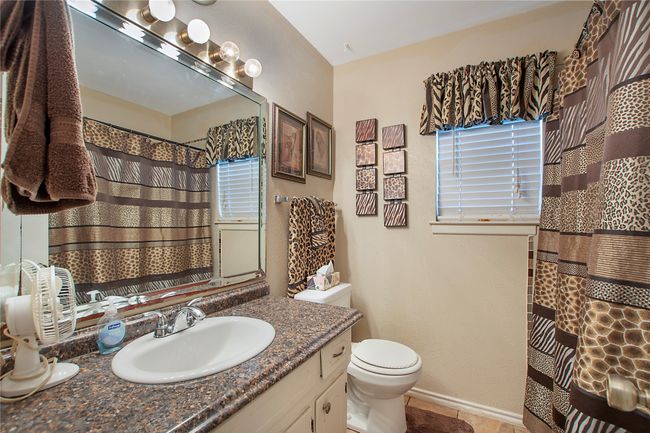 Full bathroom with a shower with curtain, toilet, baseboards, tile patterned floors, and vanity | Image 8