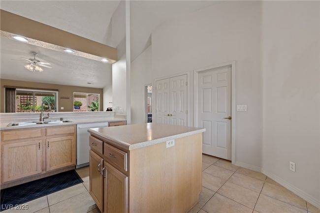 Kitchen featuring white dishwasher, light brown cabinetry, light tile patterned flooring, a towering ceiling, and light countertops | Image 16