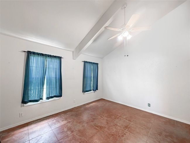 Empty room featuring tile patterned floors, ceiling fan, lofted ceiling with beams, and baseboards | Image 5