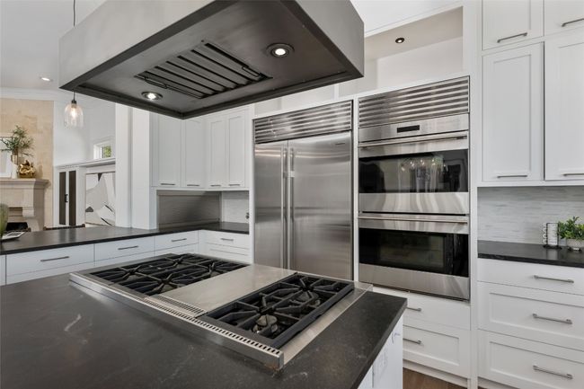 Kitchen featuring appliances with stainless steel finishes, exhaust hood, backsplash, white cabinetry, and recessed lighting | Image 11