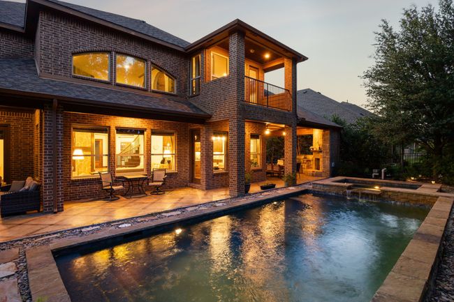 Back of house at dusk with a balcony, brick siding, and roof with shingles | Image 36