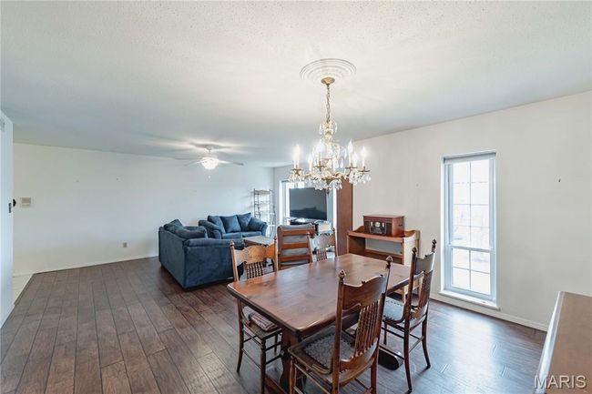Dining area featuring dark wood finished floors, ceiling fan, and a chandelier | Image 15