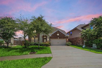 Welcome to this stunning 5-bedroom, 3-bath home in the sought-after Lakes of Bella Terra community. The front yard is beautifully landscaped with mature trees and lush greenery, providing excellent curb appeal. | Image 1