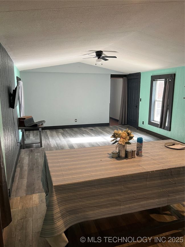 Living room featuring lofted ceiling, wood-type flooring, ceiling fan, baseboards, and a textured ceiling | Image 6