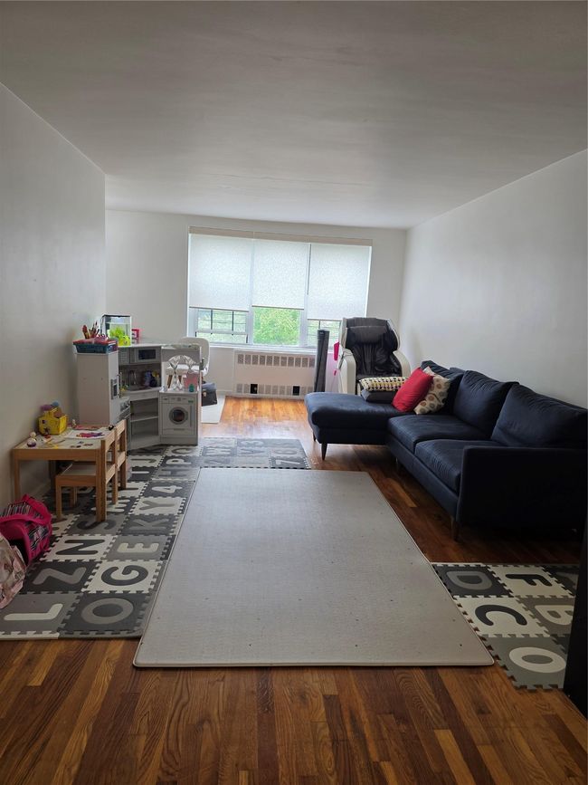 Living area featuring wood finished floors and radiator | Image 5