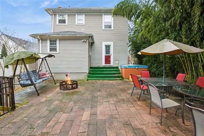 Rear view of house with a patio area, outdoor dining area, entry steps, and an outdoor fire pit | Image 24