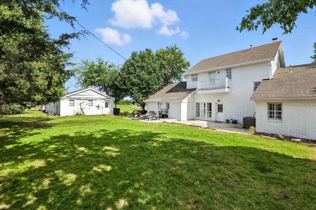 Rear view of house with a patio, a balcony, brick siding, a shingled roof, and a lawn | Image 31