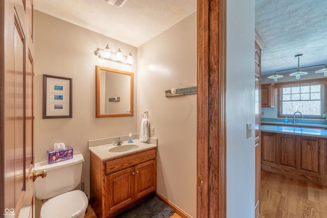bathroom with wood finished floors, a textured ceiling, vanity, and toilet | Image 16