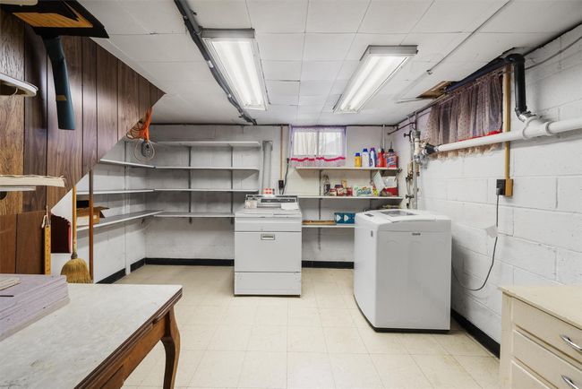 Laundry area featuring concrete block wall, laundry area, washer and clothes dryer, and light floors | Image 33
