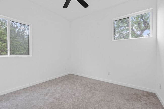 Carpeted empty room with a ceiling fan, baseboards, and plenty of natural light | Image 32