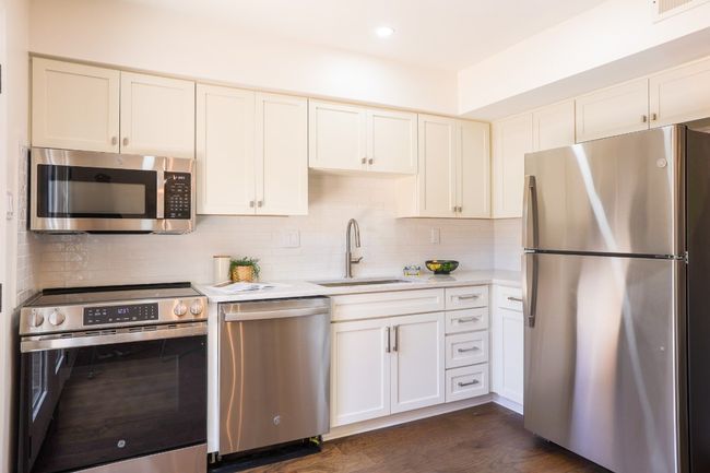 Kitchen with stainless steel appliances, light quartz countertops, backsplash, dark engineered hardwood finished floors, and recessed lighting. | Image 13