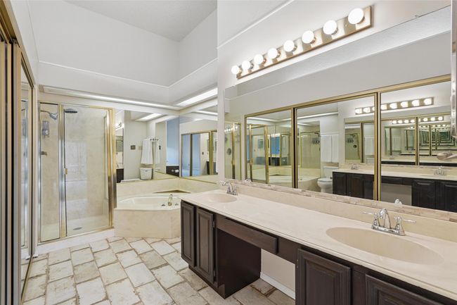 Bathroom with a jetted tub, double vanity, separate shower, toilet, and tile flooring | Image 12