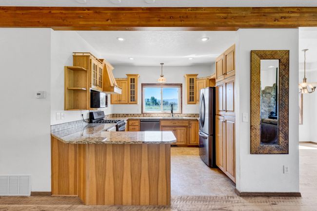 Kitchen featuring stainless steel appliances, a peninsula, light stone counters, open shelves, and recessed lighting | Image 20