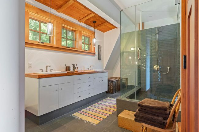 Full bath featuring double vanity, tile patterned floors, a shower stall, and beamed ceiling | Image 21