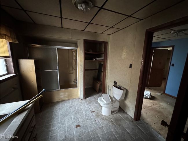 Full bathroom with a drop ceiling, toilet, and shower / bath combination with glass door | Image 5