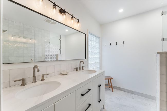 Primary bathroom has elegant finishes, stunning walk-in showers, and a sleek double-sink vanity | Image 15