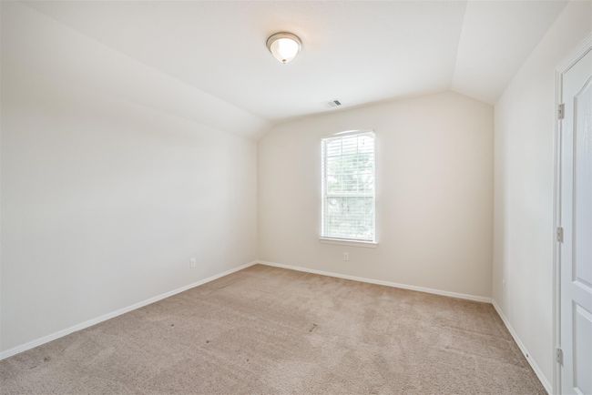 This is a bright, upstairs bedroom 2 with neutral carpeting, an overhead light fixture, and a window allowing natural light. The walls are painted a light color, creating a spacious and airy feel. | Image 24