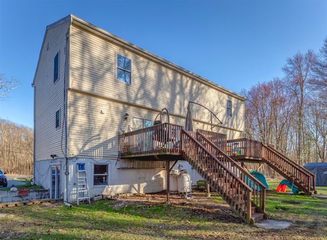 Rear view of property with stairs, a deck, and a lawn | Image 43